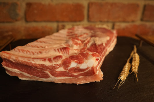 Portion of Bone in Pork Belly on a slate chopping board 