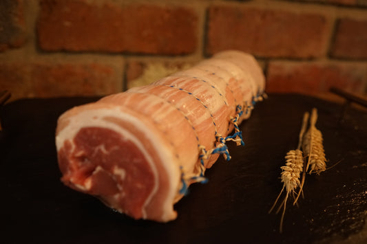 A large Boned & Rolled Pork Belly on a slate chopping board