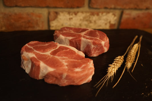 2 Pork Collar Steaks on a slate chopping board