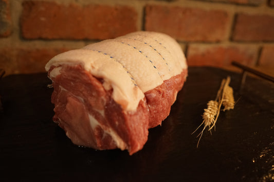 A large Rolled Pork Collar Roast on a slate chopping board